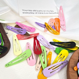 Colorful matte teardrop snap hair clips in various vibrant shades on white fabric
