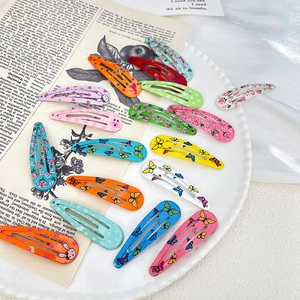 Assorted colorful snap hair clips with floral and rabbit prints on a white decorative tray