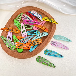 Colorful floral and animal print metal snap hair clips set on a wooden tray