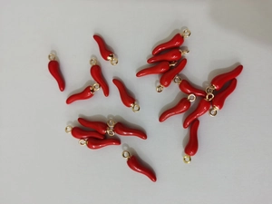 Macro detail of red chili pendants with gold rings for DIY jewelry making