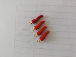 Macro shot of 4 red chili pepper charms with glossy enamel and gold metal rings
