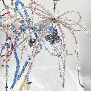 Macro shot of handmade beaded bow keychain with clear acrylic beads and butterfly charm
