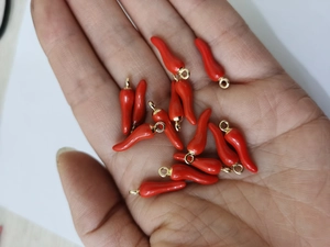 Detailed macro view of small red chili alloy pendants for DIY jewelry making