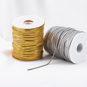 Close-up of gold and silver plated stainless steel flat curb chains on white plastic reels