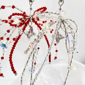 Macro view of handmade red beaded bowtie keychain with acrylic crystals and silver butterfly charms
