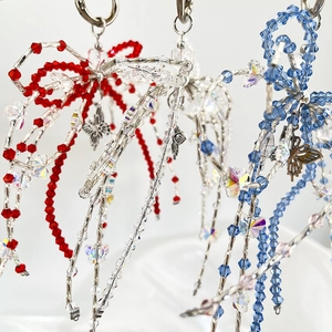Detail of handmade beaded bow keychain with clear acrylic crystals and metal butterfly charm