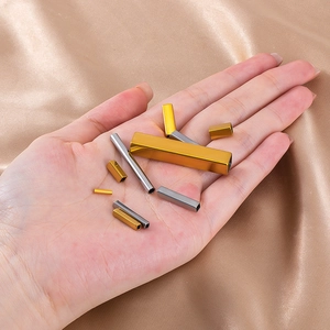 Macro view of assorted small stainless steel tubes in gold and silver on hand