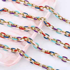 Detailed close-up of multi-color enamel gold link chain on a pink marble tray