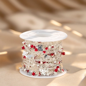 Silver chain with red rhinestones and butterfly charms wrapped on a spool for DIY jewelry