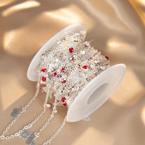 Macro view of copper chain with red rhinestones and butterfly charms on a spool