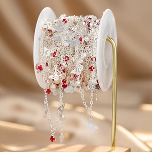 Detail of silver chain rolls with butterfly charms and red gemstones for DIY jewelry