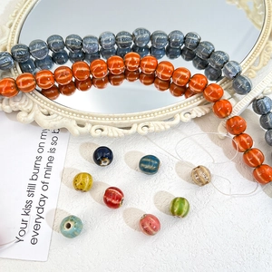 Macro shot of pumpkin-shaped ceramic beads with natural kiln-fired glaze on white surface
