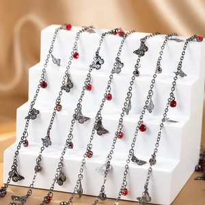 Detail of copper butterfly pendants with red crystals on silver-black chain necklaces