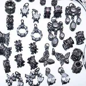 Dettaglio macro di ciondoli in zircone gunmetal con motivi a stella, farfalla e fiori