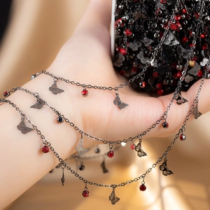 Close-up of black copper chain with red rhinestones and hollow butterfly charms for DIY jewelry