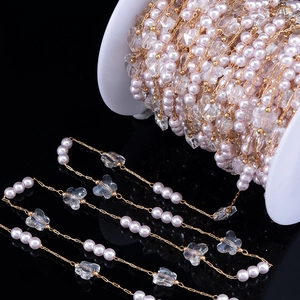 Detailed close-up of pink imitation pearl and butterfly bead chain on a spool for DIY jewelry
