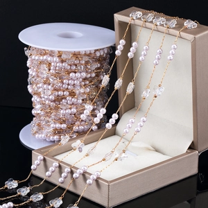 Detailed close-up of DIY pearl and butterfly beads on a golden chain spool