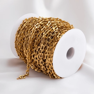 Macro view of gold stainless steel geometric chain links on a white spool for DIY jewelry