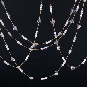 Close-up of gold chain with white pearls and clear butterfly pendants for DIY jewelry