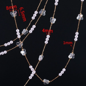 Macro detail of 4mm pearl and crystal butterfly charms on a 1mm gold-plated copper chain