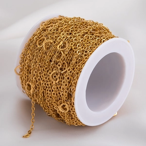 Detail of gold heart-shaped link chain for jewelry making on a white plastic spool