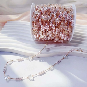Close-up of pink pearl and faceted crystal bead chain on a gold reel for DIY jewelry