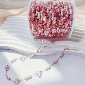 Detail of pink crystal butterfly and pearl chain on a roll for DIY jewelry making