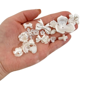 Onregelmatige parelwitte DIY-kralenset met bloemen en hartvormen in de hand