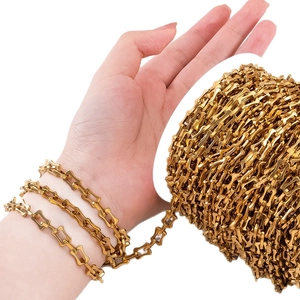 Golden stainless steel bone-shaped DIY chain on spool with hand-worn scale comparison