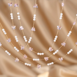 Golden pearl chain with pink butterfly charms on champagne silk background