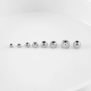 Detailed macro view of various sizes of silver stainless steel pumpkin beads for DIY jewelry
