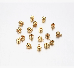 Vista macro di perle schiacciabili dorate con perni laterali per creazione braccialetti DIY