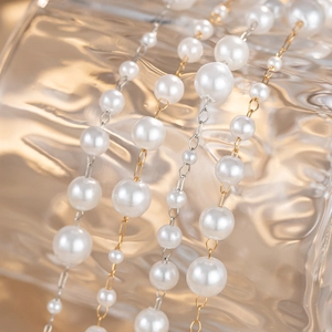 Multi-layer pearl chain necklace with gold and silver link details on glass