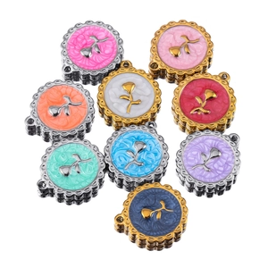 Detail view of nine colorful rose flower charms for DIY jewelry making in various finishes