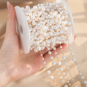 Detailed view of white faux pearl chain with gold metal links on a plastic spool
