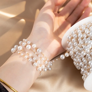 Detailed view of DIY pearl chain with gold beads on elegant silk fabric background