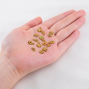 Detailed shot of mini gold star pendants with colorful rhinestones in hand for DIY jewelry