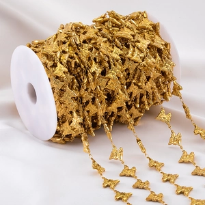 Macro shot of gold butterfly chain jewelry accessories wound on a white spool