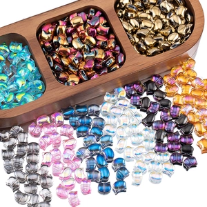 Macro view of iridescent Czech glass cat head beads in a wooden tray for DIY jewelry