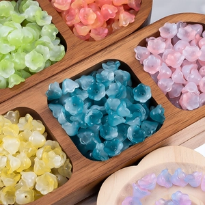Detailed view of colorful gradient lily of the valley glass beads in a wooden tray