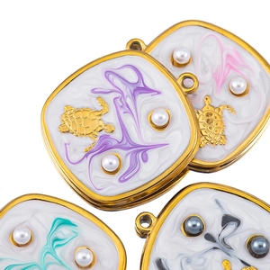 Detail of square sea turtle charms with marble enamel and inlaid pearls for DIY jewelry
