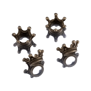 Detail of four antique bronze crown charms for DIY jewelry making on white background