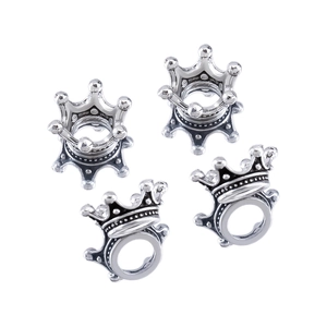 Detailed macro view of four vintage silver crown-shaped jewelry charms on white background