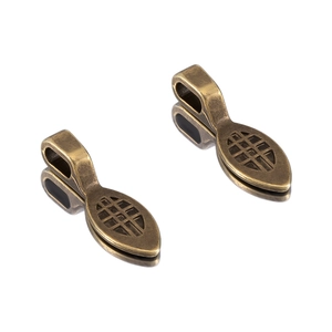 Detailed macro view of two antique bronze alloy charms with hollow mesh texture pattern