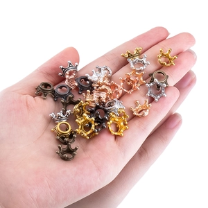 Miniature crown pendants in assorted metallic finishes shown in hand for scale