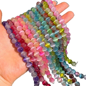 Hand hält bunte 8mm Katzenaugenperlen für DIY-Schmuckherstellung und Armband-Design
