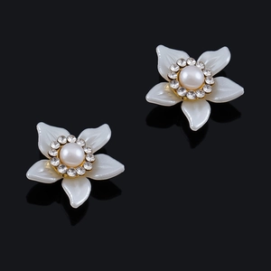 Detalle de pendientes de flor con perlas blancas y cristales sobre una base dorada