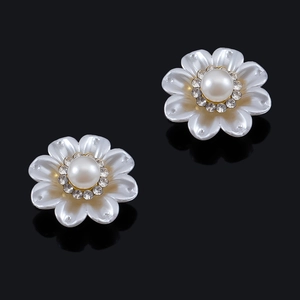 Primer plano detallado de pendientes de flores con perlas de concha y detalles de cristal dorado