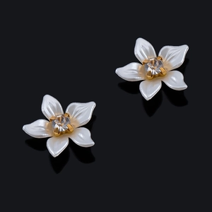 Vista detallada de pendientes de flor en esmalte blanco con un centro de circón brillante