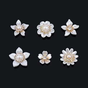 Detalle de seis estilos de accesorios florales con perlas y strass sobre un espejo negro